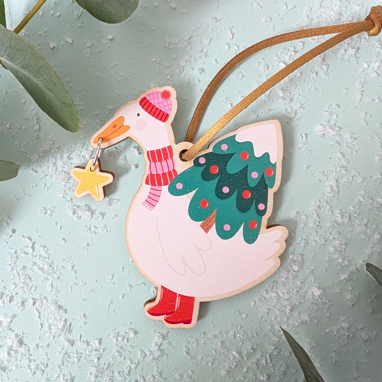 Decorative duck ornament with a tree and star on a light blue background