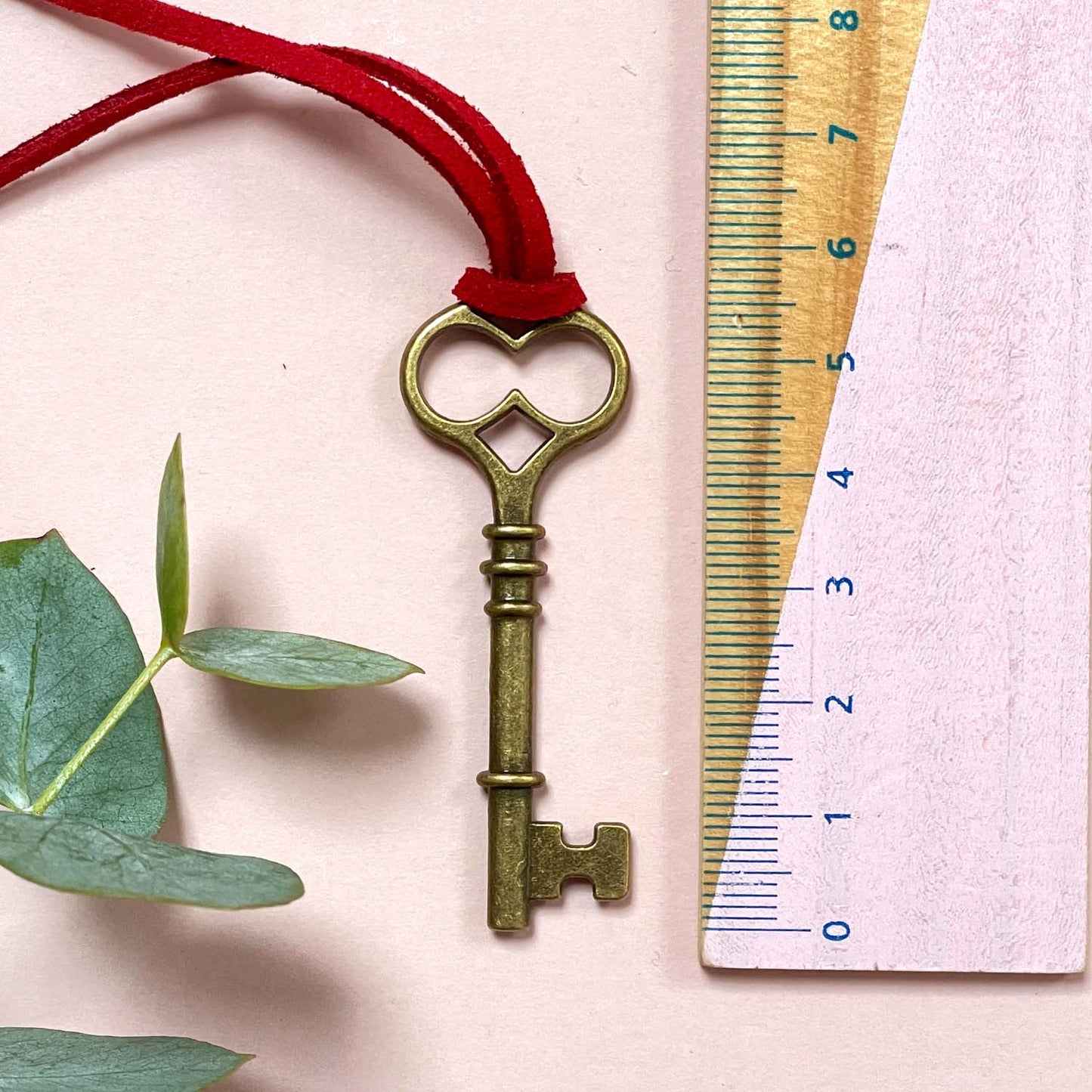 The Santa key decoration on a red string with a ruler for scale on a light pink background.