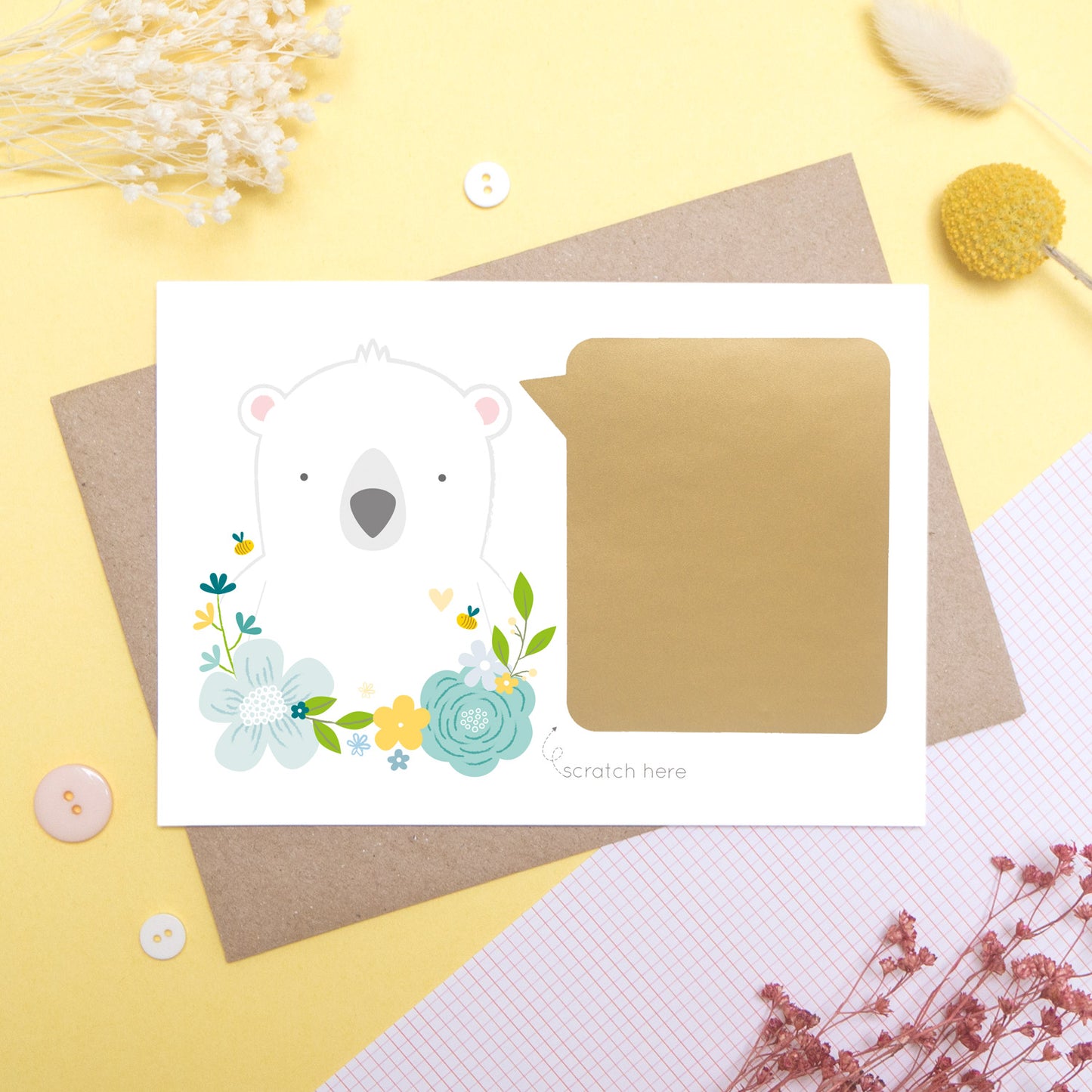 A personalised godparent scratch card before it has been scratched off. This is how the cards will arrive. This one has been shot on a yellow background with floral props. It features a white bear with a blue theme.