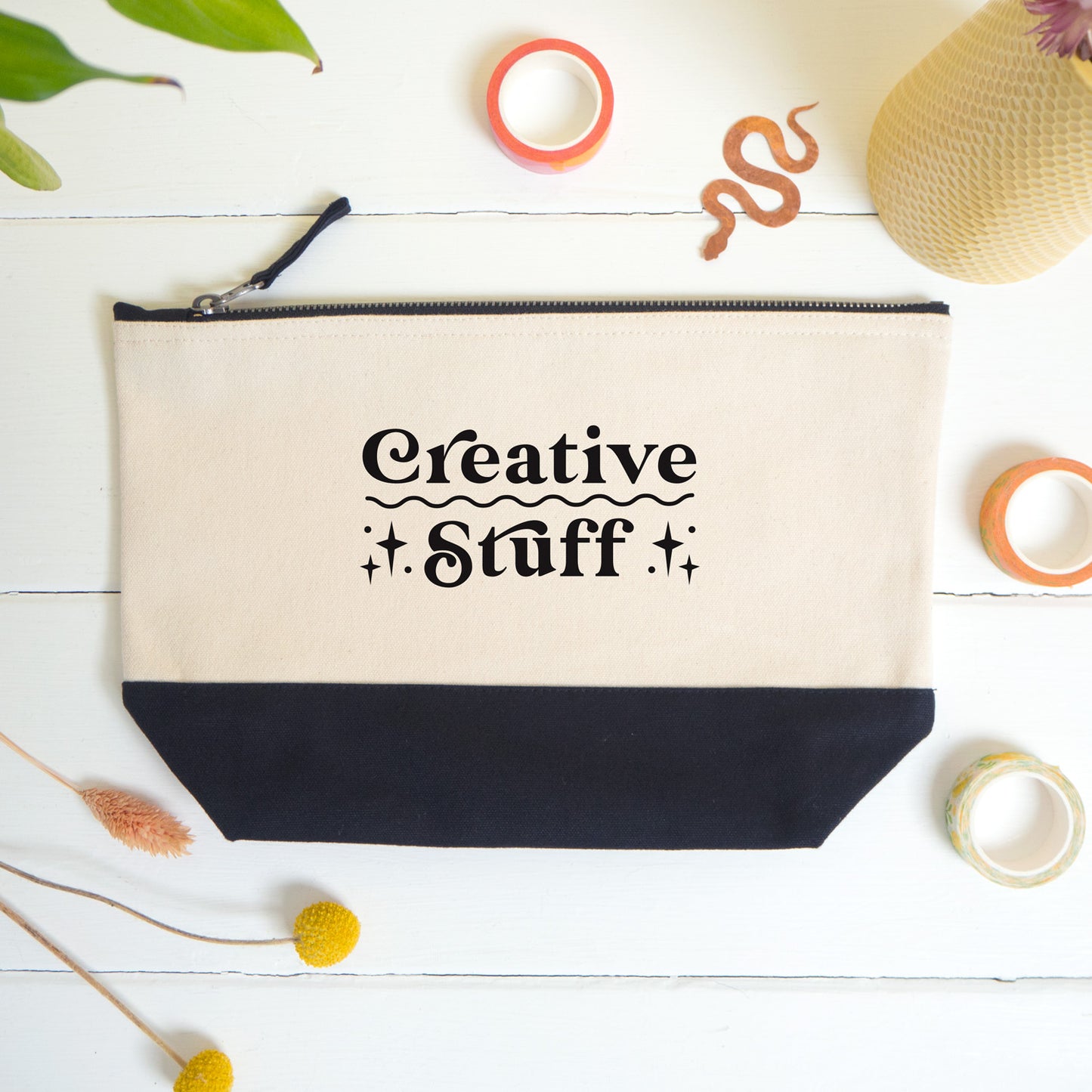 A flatlay view of the creative stuff project bag shot on a white surface surrounded by dry flowers, washi and a snake bookmark.