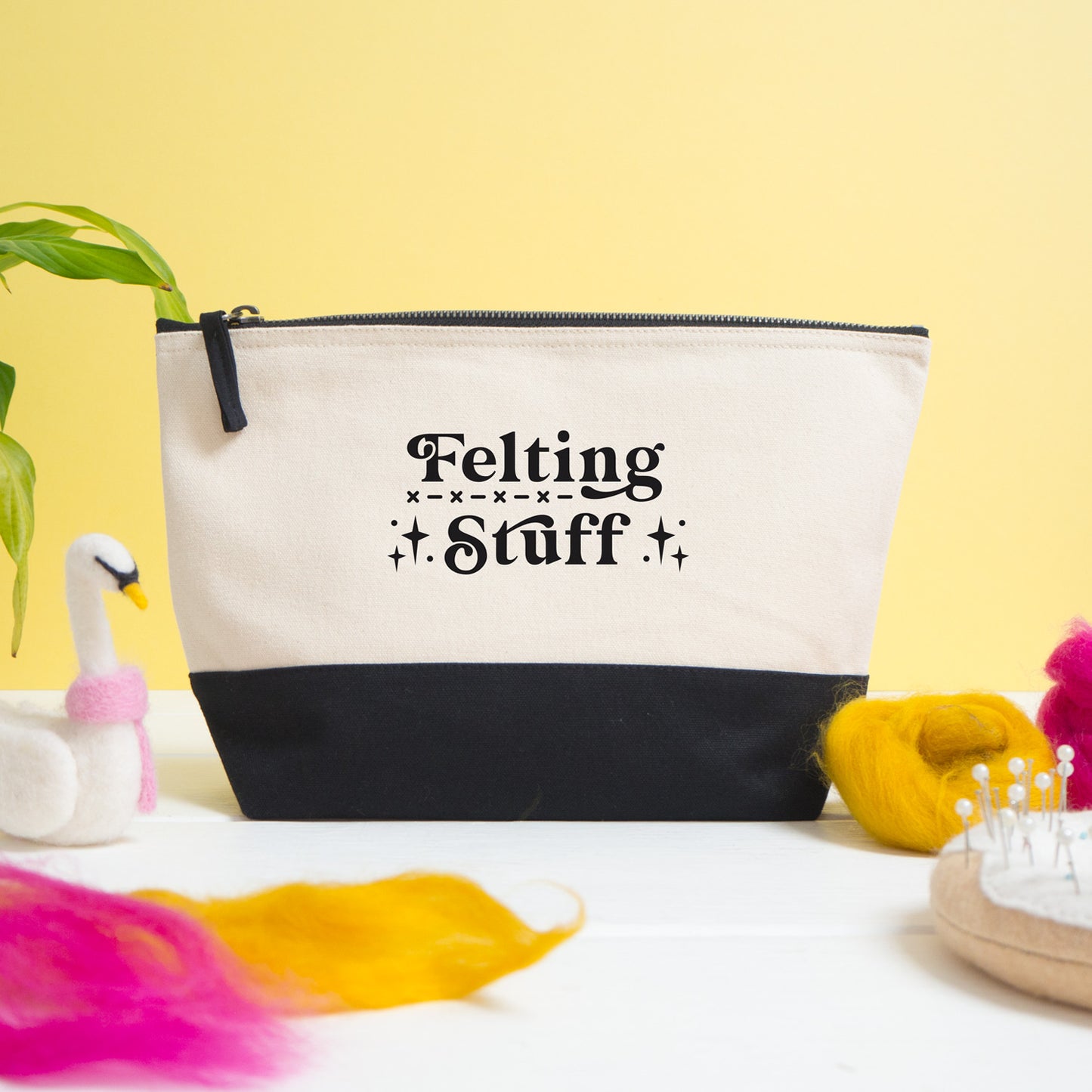 A felting stuff project bag shot on a white and yellow background with felting materials in the foreground.