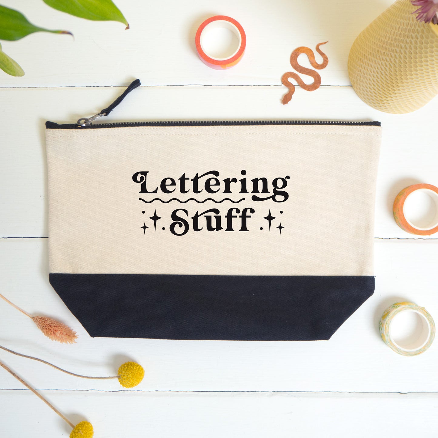 A flatlay view of the lettering stuff project bag shot on a white surface surrounded by dry flowers, washi and a snake bookmark.