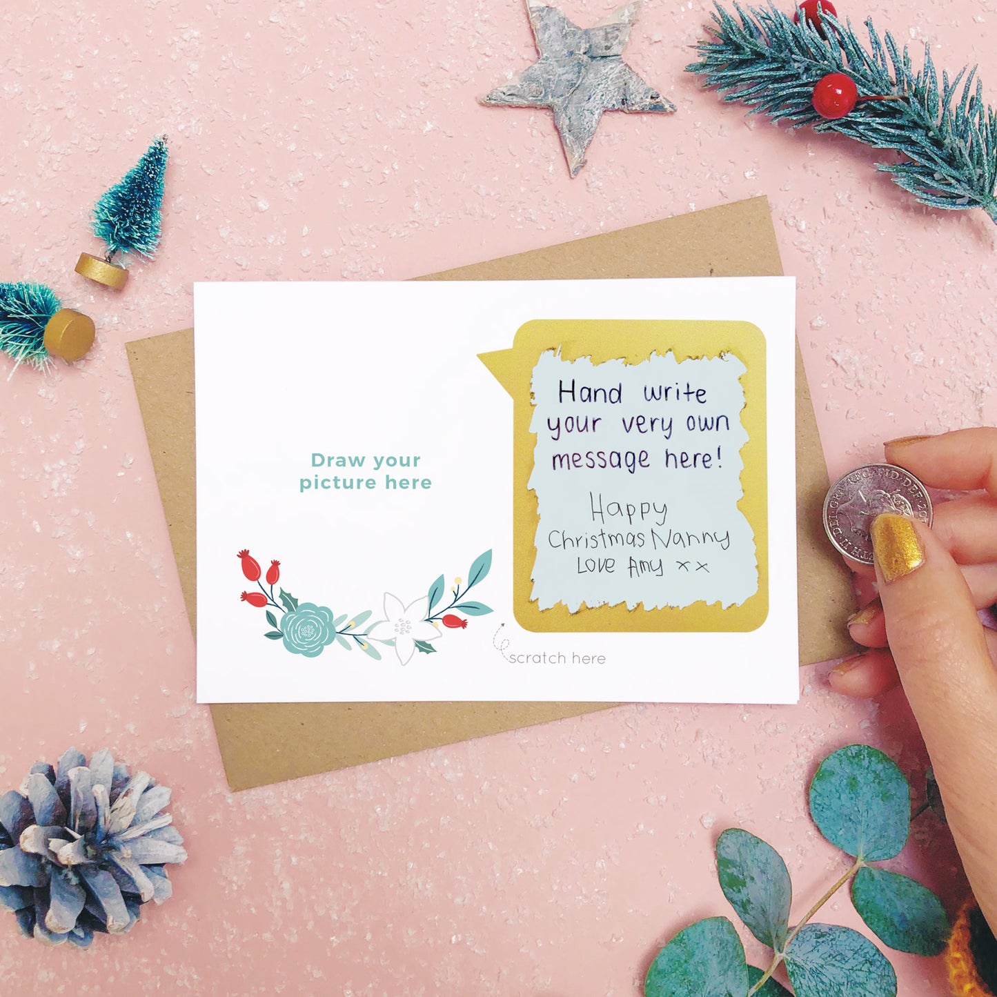 A make your own scratch card where the scratch off message has been revealed. Shot on pink with snow and greenery.