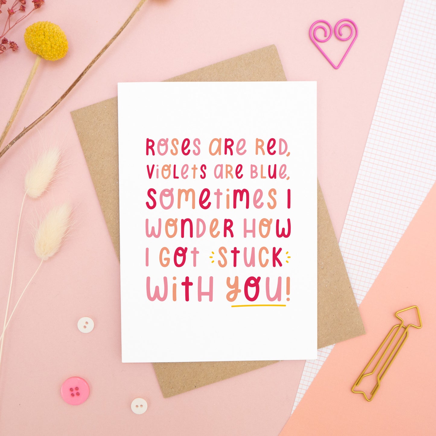 The 'stuck with you' card photographed on a pink background with dried flowers, buttons and paper clips as props.