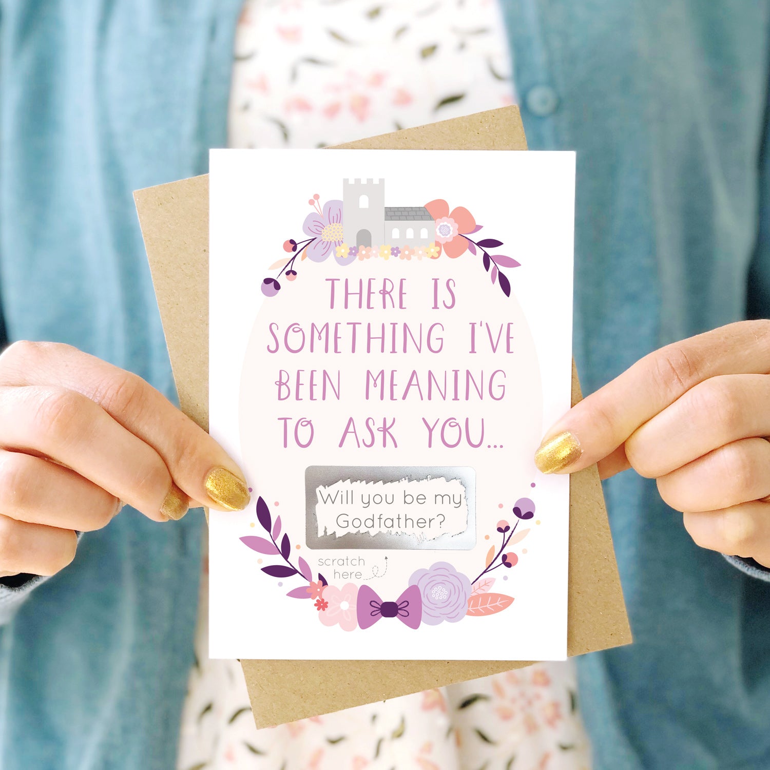 A will you be my godfather scratch and reveal card being held in front of a white dress and blue cardigan. The design features a church, simple florals and a scratch off panel in silver. This is the purple palette.