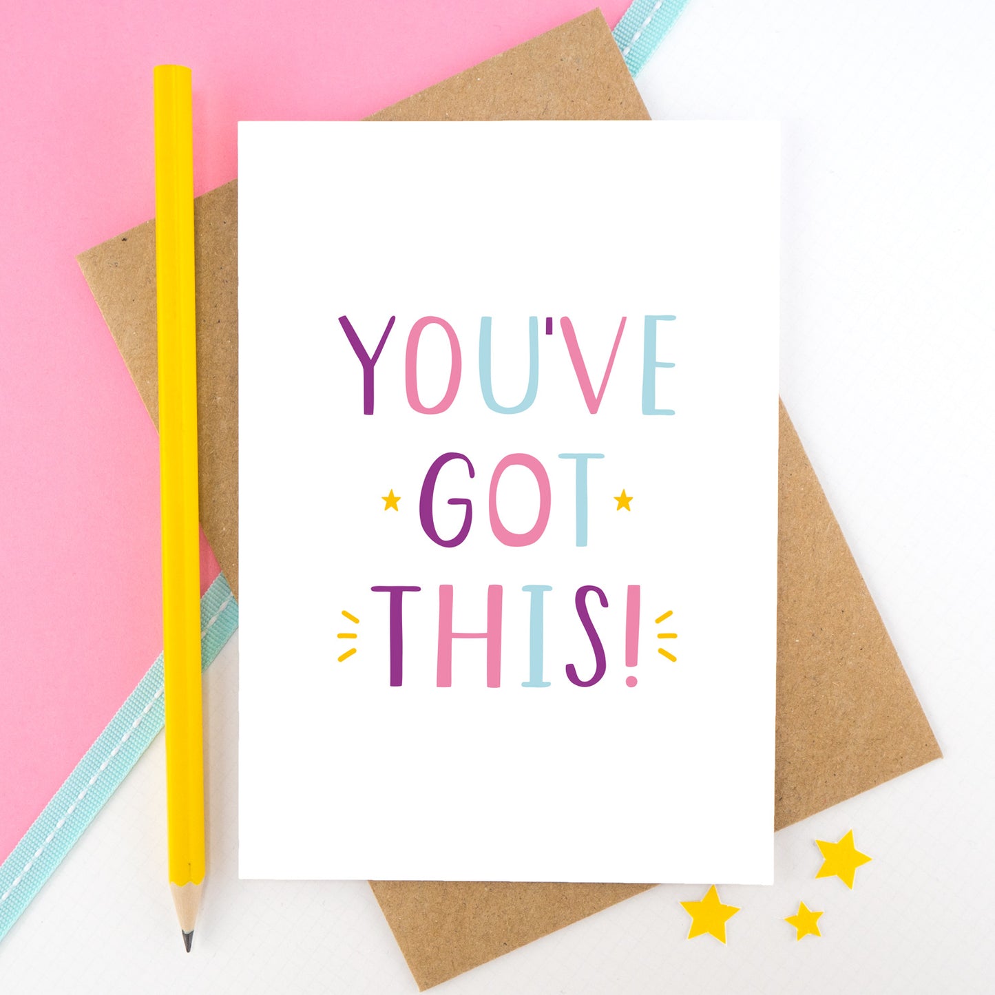 You've got this! A positive encouragement card photographed on a pink and white background with a teal ribbon and bright yellow pencil. The lettering on this card is in pink, purple and blue.