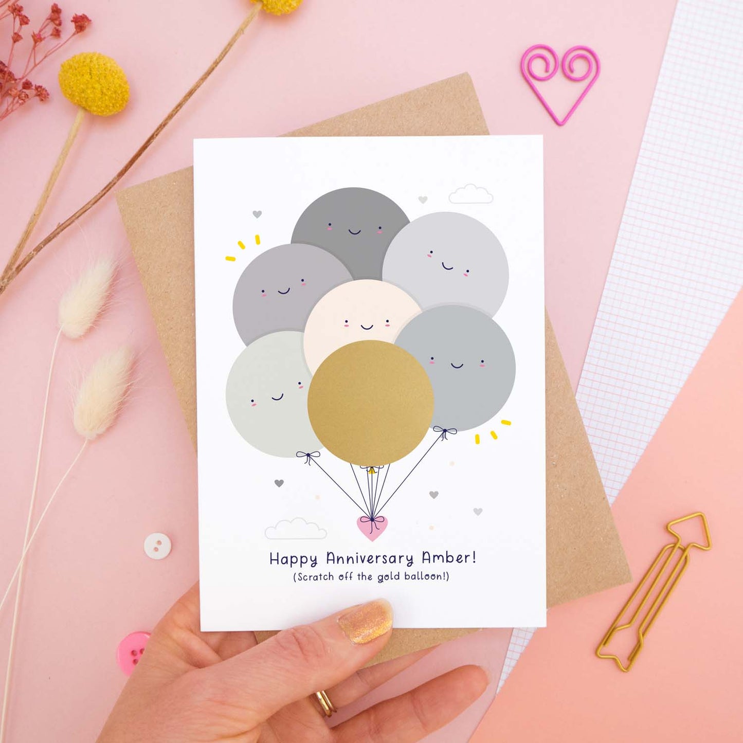 A flat lay view showing the anniversary scratch card with the gold balloon before it is scratched off by the recipient.