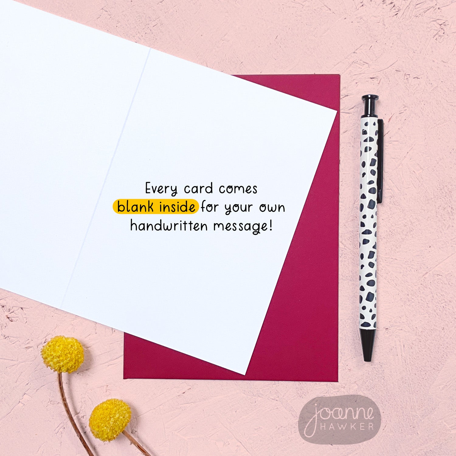 An image showing that the inside of the greetings card is blank for your own handwritten message. The card has a red envelope and it has been photographed on a pink background next to yellow flowers and a pen for scale.