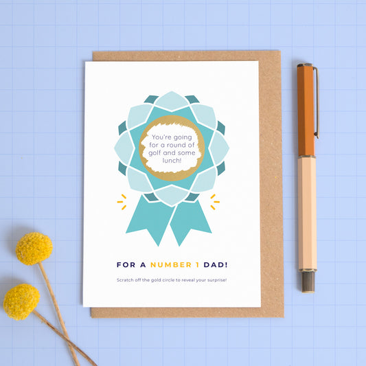 A number 1 dad scratch card featuring a rosette with a scratch off centre where your personalised message will be hidden. This card is showing the blue colour palette.