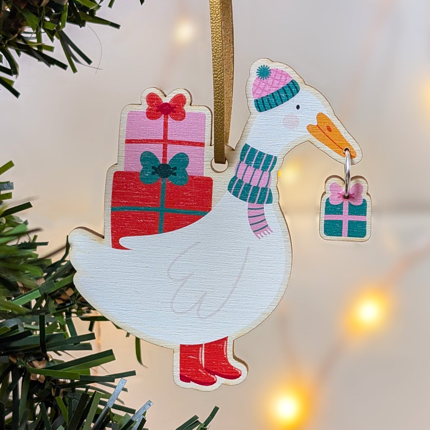 Decorative duck ornament with a gift and scarf on a Christmas tree.