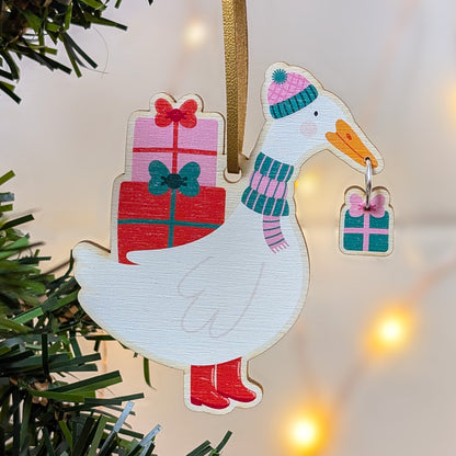 Decorative duck ornament with a gift and scarf on a Christmas tree.