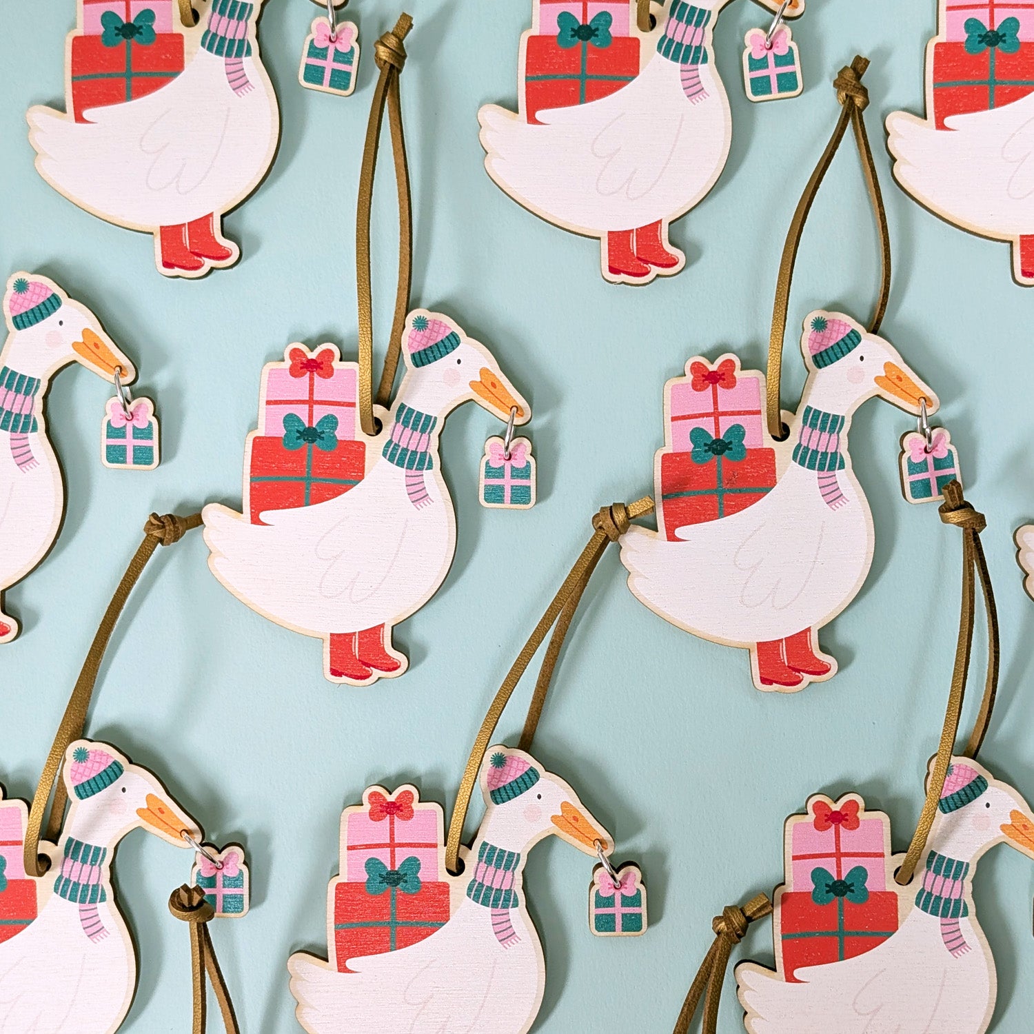 Decorative goose ornaments with presents in their beaks on a light blue background