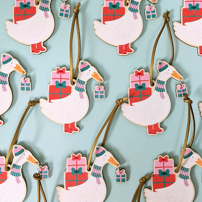 Decorative goose ornaments with presents in their beaks on a light blue background