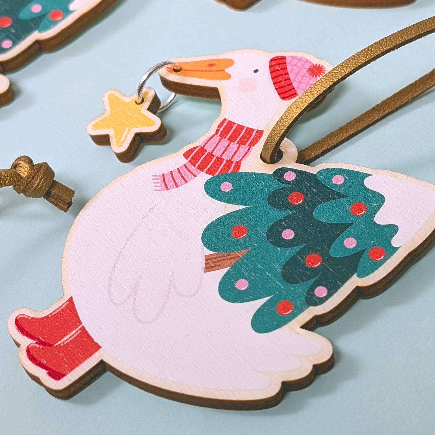 Decorative duck decoration shaped like a goose with a Christmas tree design on a light blue background.