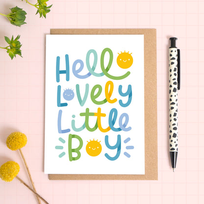 A new baby boy greeting card with 'Hello Lovely Little Boy' text on a pink background with a pen and flowers.