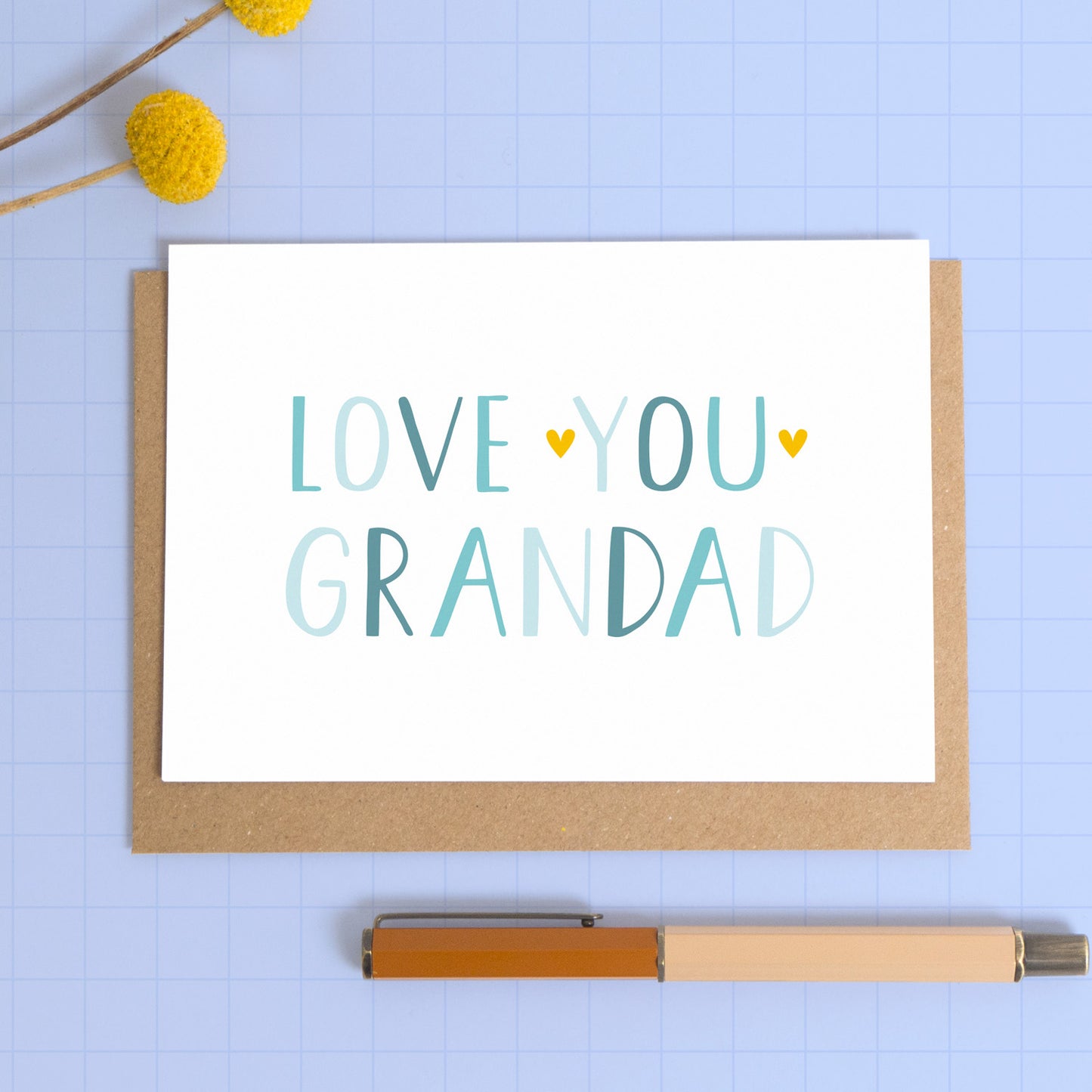 This image shows a love you grandad card in landscape format photographed on a kraft brown envelope with a blue background.