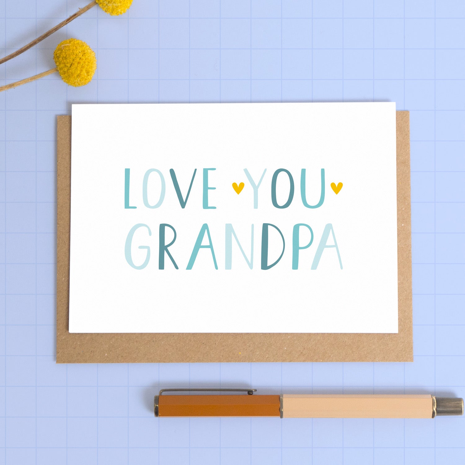 This image shows a love you grandpa card in landscape format photographed on a kraft brown envelope with a blue background.