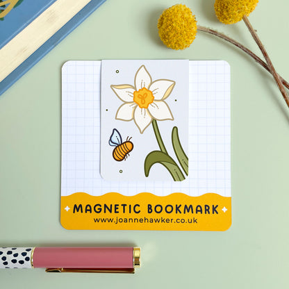 Magnetic bookmark with a cream narcissus flower and bee design on a light green background