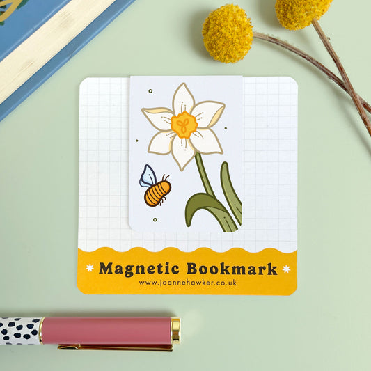 Magnetic bookmark with a cream narcissus flower and bee design on a light green background