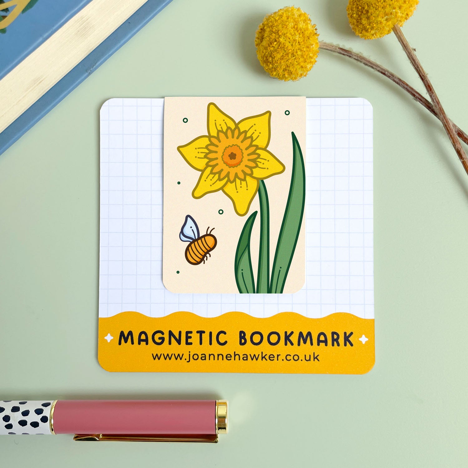 Magnetic bookmark with a yellow daffodil flower and bee illustration on a light green background.