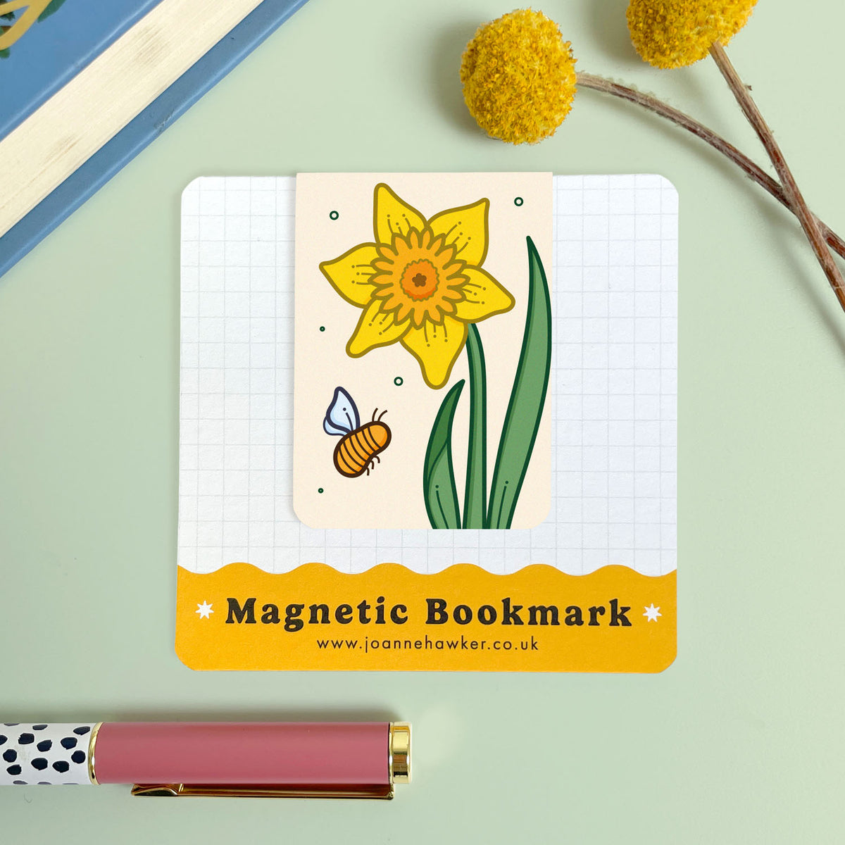 Magnetic bookmark with a yellow daffodil flower and bee illustration on a light green background.