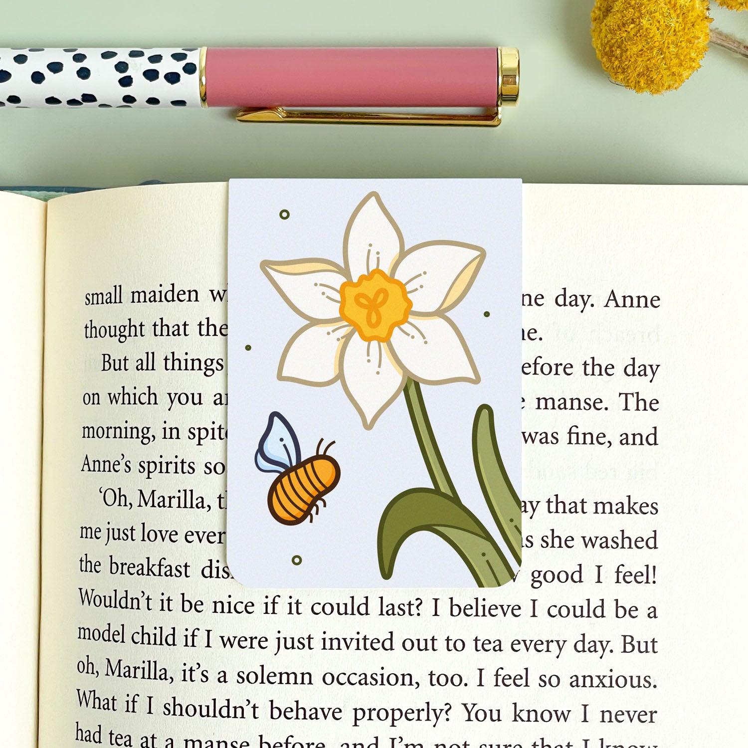 Floral narcissus bookmark with bee illustration on an open book