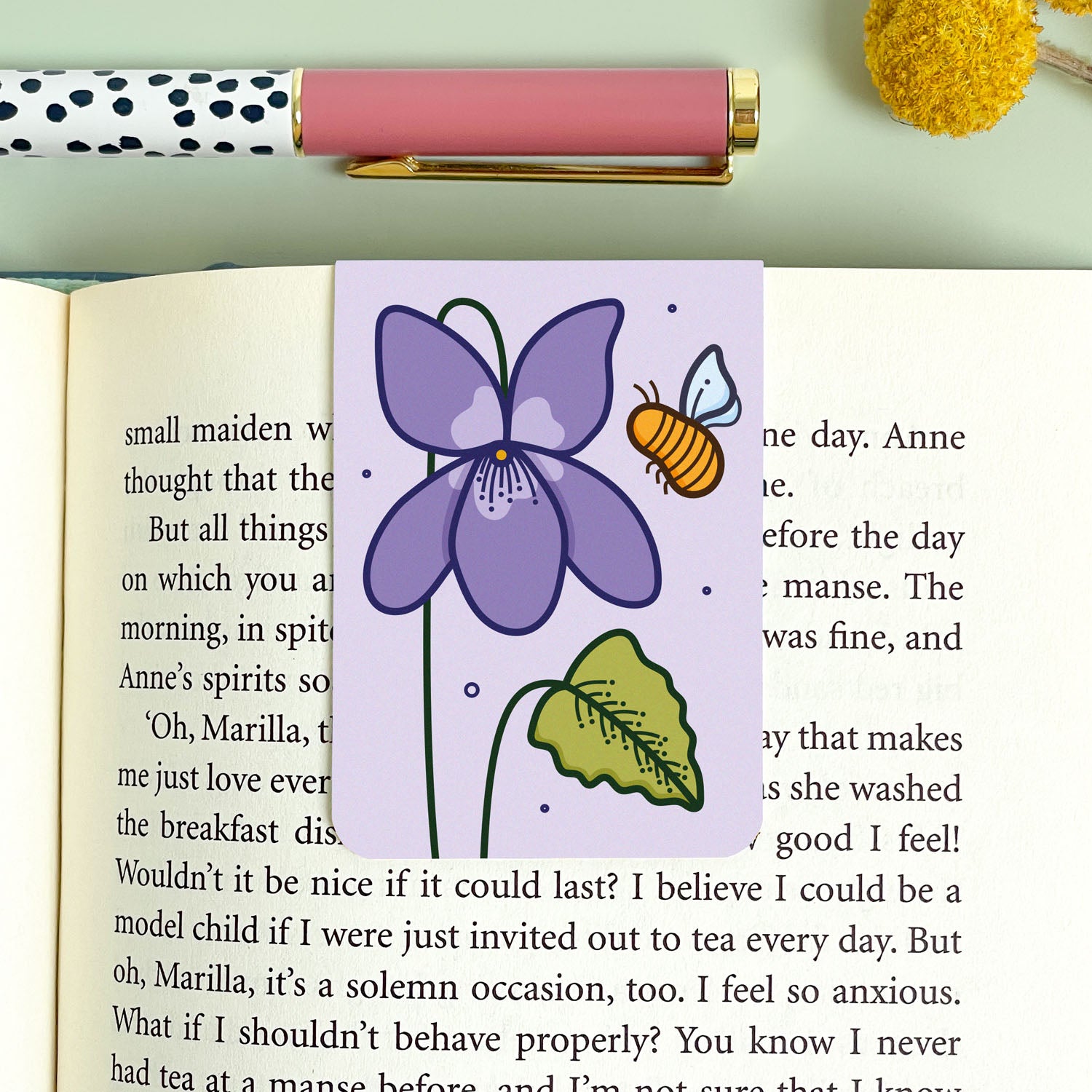Floral bookmark with a purple flower and bee on an open book
