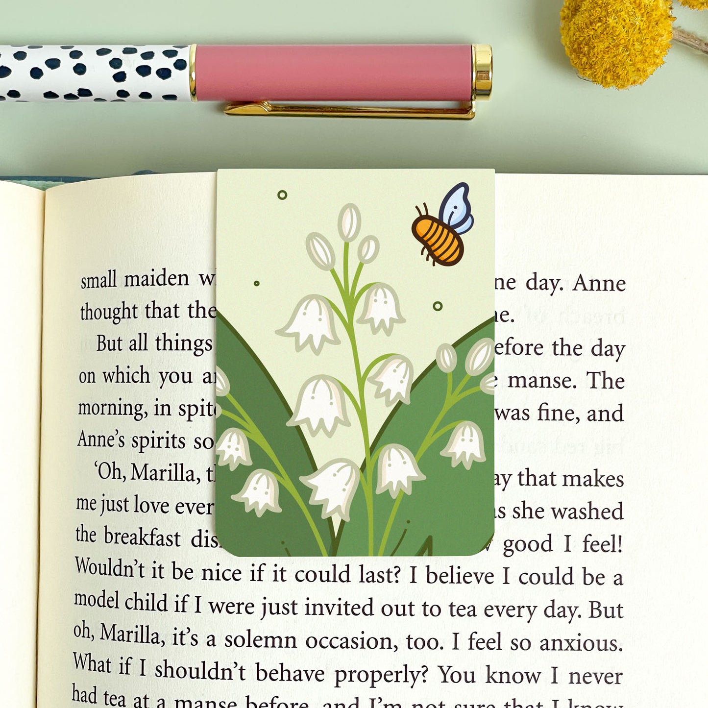 Bookmark with a floral lily of the valley design and a pen on a light green background