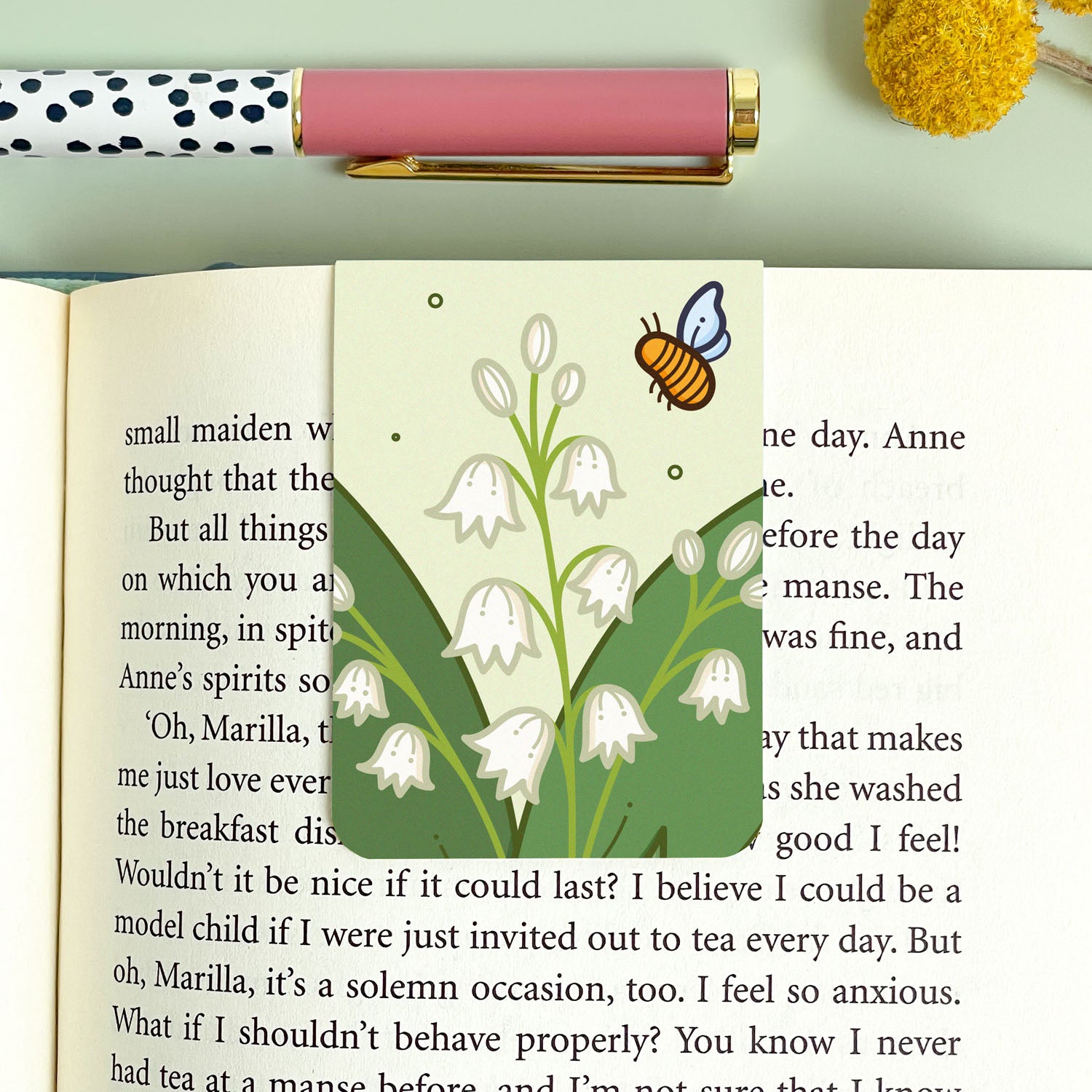 Bookmark with a floral lily of the valley design and a pen on a light green background