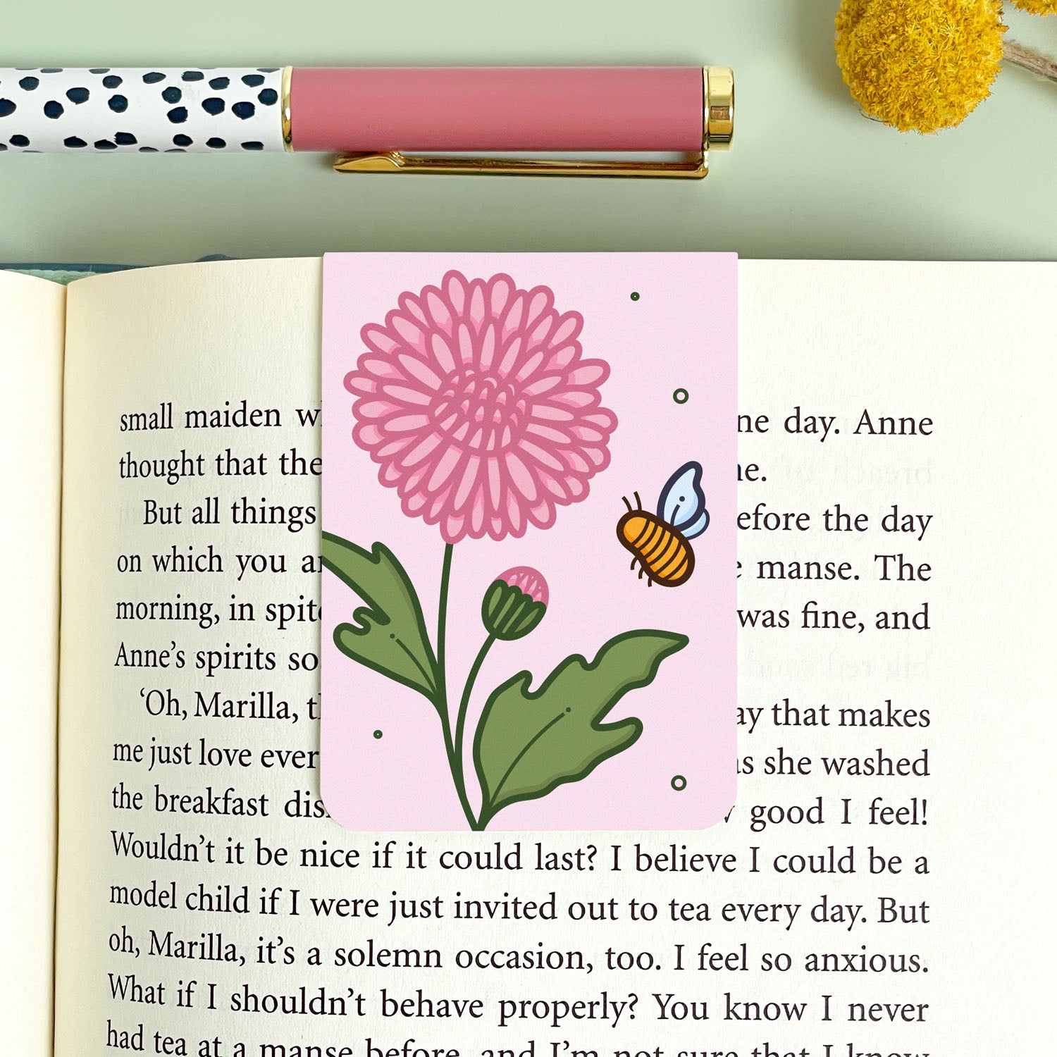 Floral chrysanthemum bookmark on an open book with a pen and decorative elements.