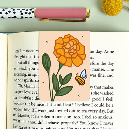 Floral marigold bookmark on an open book with a pen and decorative elements.