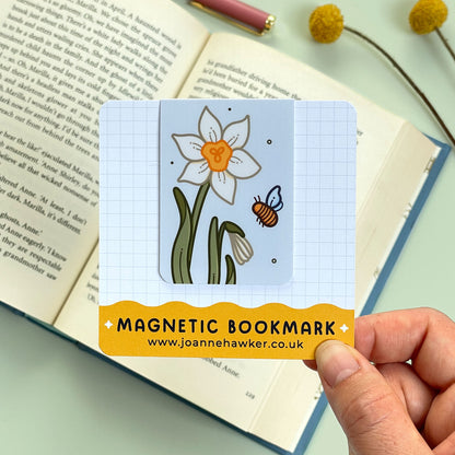 Magnetic bookmark with floral narcissus design held over an open book