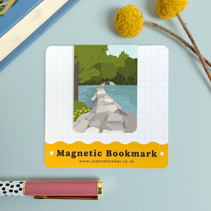 The Tarr Steps bookmark featuring the iconic view of the steps across the river Barle on Exmoor. The backing card is laid on a light blue surface with a pen and pom pom flowers.