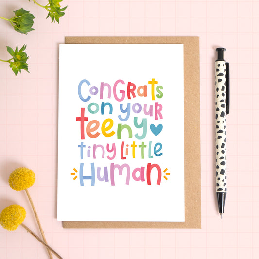 This tiny little human newborn congratulations card is perfect for anyone welcoming a new addition to their family! It features rainbow text which reads: 'congrats on your teeny tiny little human', and is a great way to congratulate new parents on the arrival of their new baby.
