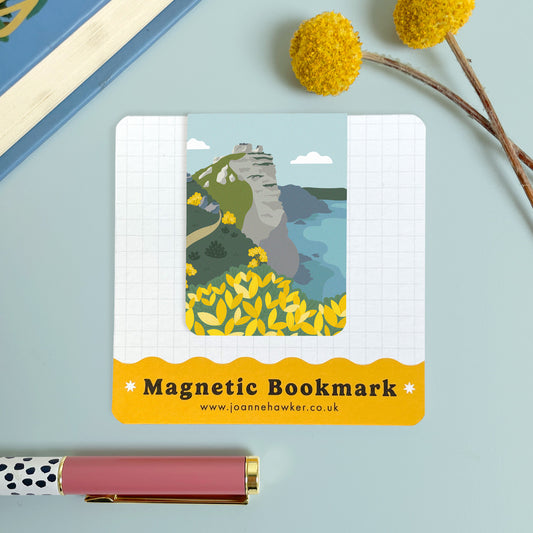 The Valley of Rocks bookmark featuring the famous rock formation on the Exmoor coast with views of the Bristol Channel. The backing card is laid on a light blue surface with a pen and pom pom flowers.