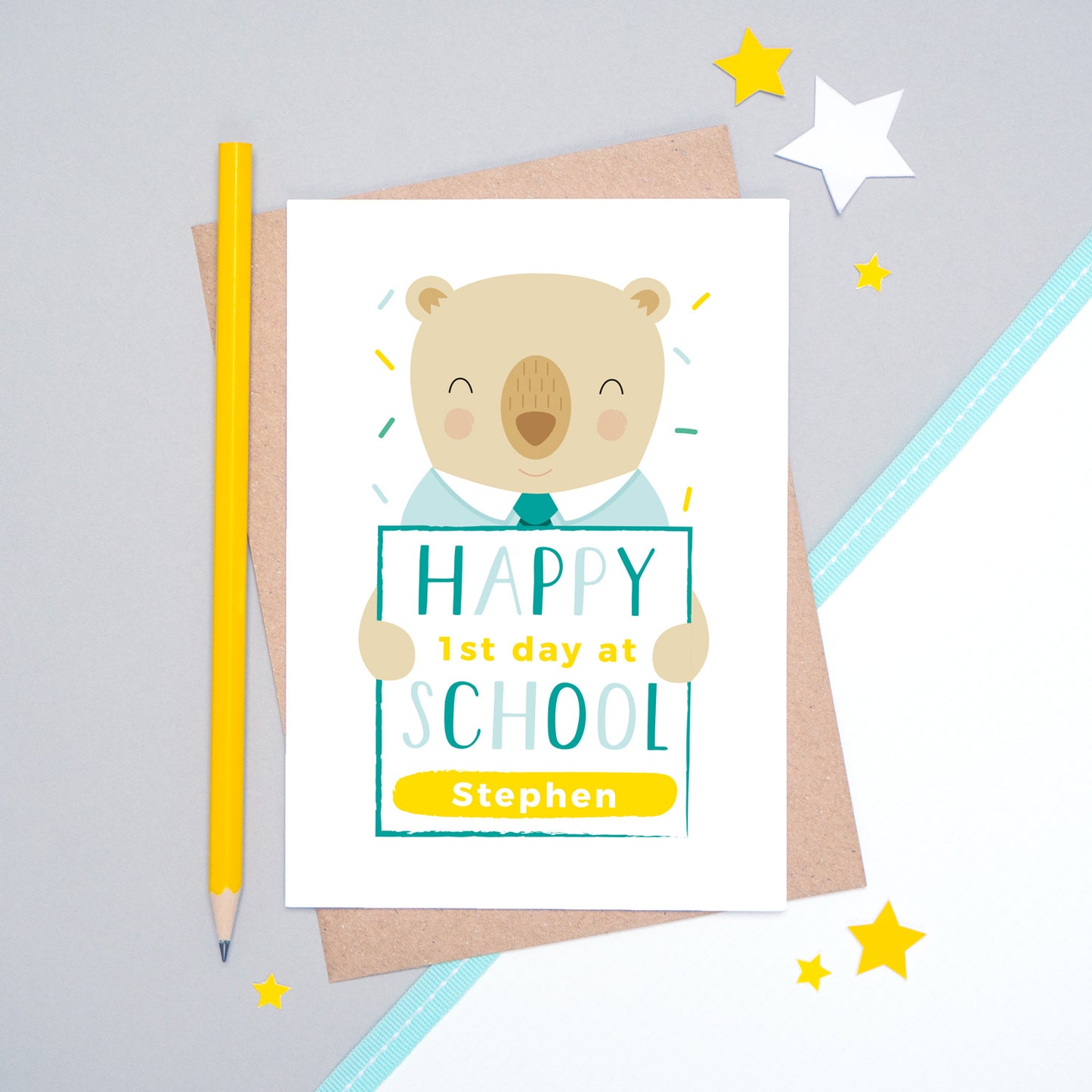 A happy 1st day at school personalised card featuring a friendly bear sat on a grey and white background.