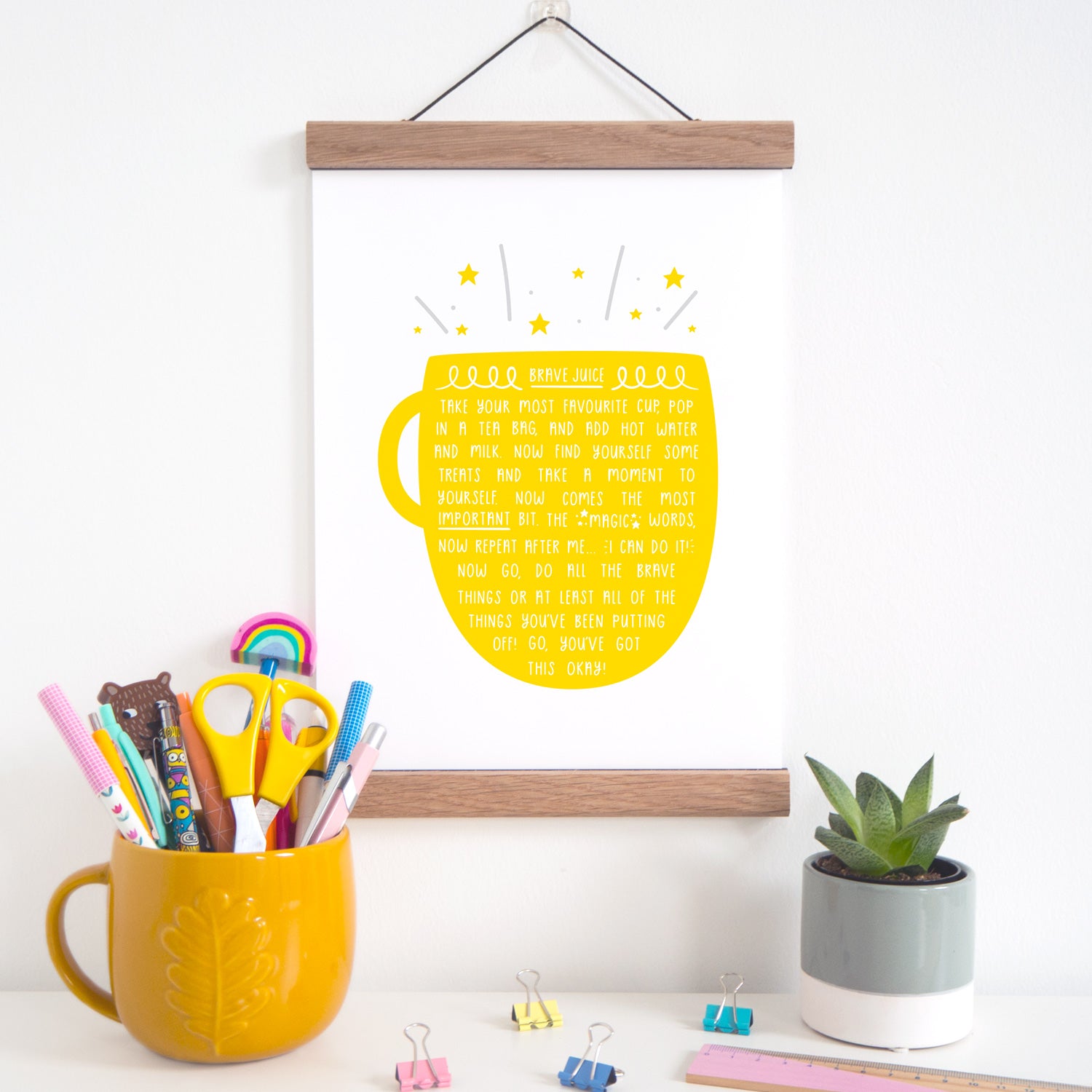 Brave juice print featuring a yellow cup of tea, which is hung on a solid oak magnetic frame.