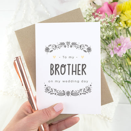 To my brother on my wedding day. A white card with grey hand drawn lettering, and a grey floral border. The image features a wedding dress and bouquet of flowers.