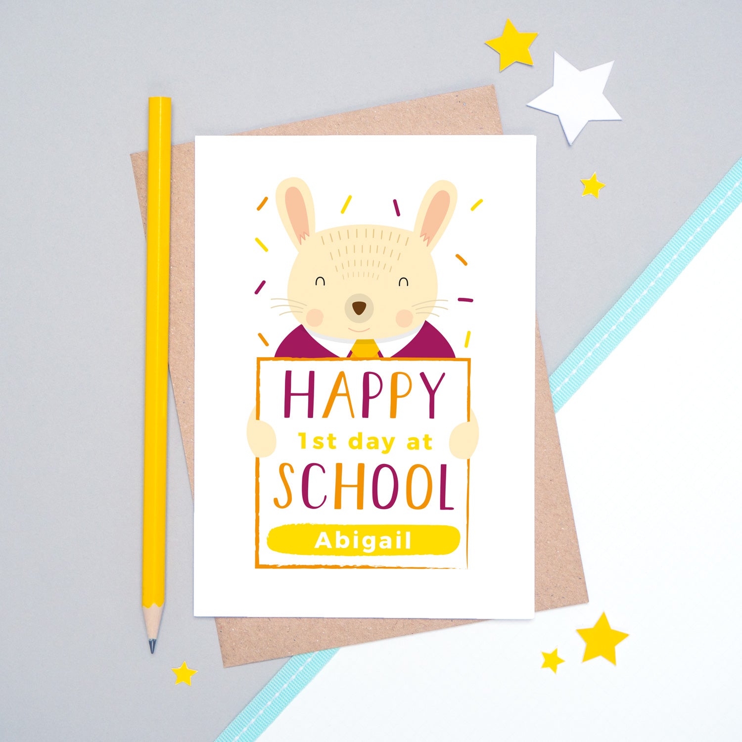 A happy 1st day at school personalised card featuring a friendly rabbit sat on a grey and white background.