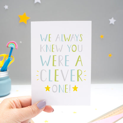 We always knew you were a clever one card held by Joanne Hawker over a grey background with white and yellow stars. The typography is in shades of green, grey and blue with two yellow stars.