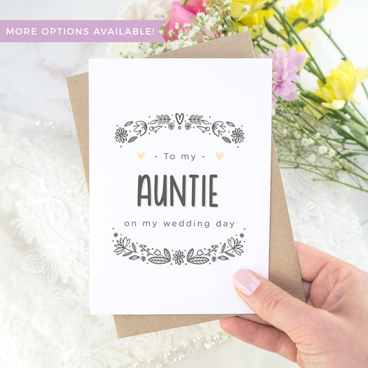 To my auntie on my wedding day. A white card with grey hand drawn lettering, and a grey floral border. The image features a wedding dress and bouquet of flowers.