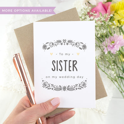 To my sister on my wedding day. A white card with grey hand drawn lettering, and a grey floral border. The image features a wedding dress and bouquet of flowers.