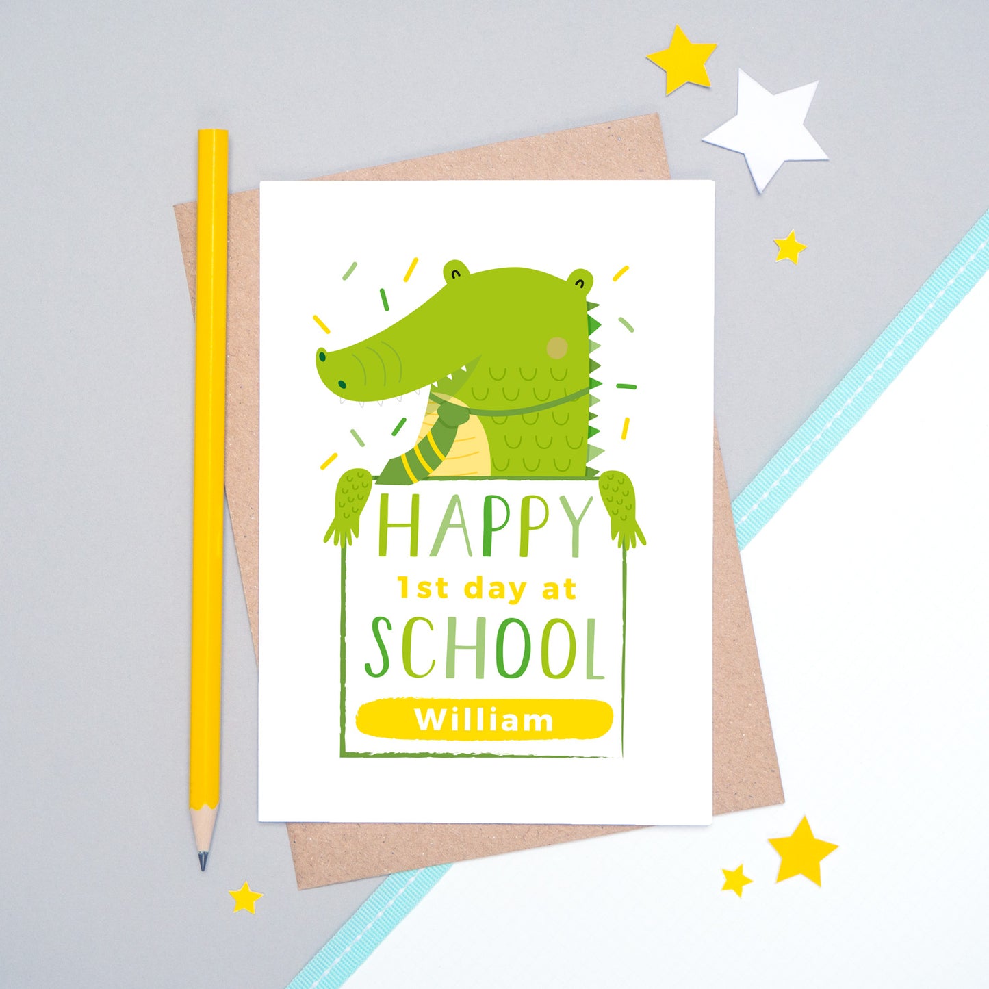 A happy 1st day at school personalised card featuring a friendly green crocodile sat on a grey and white background.