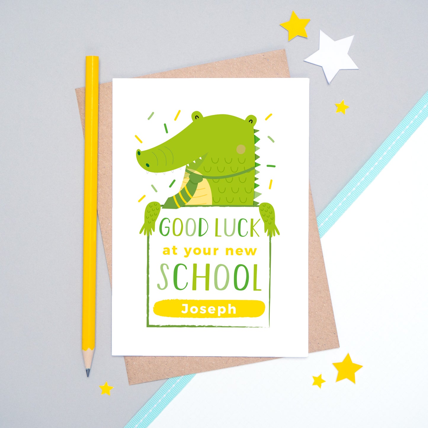 A good luck at your new school personalised card featuring a green friendly crocodile sat on a grey and white background.