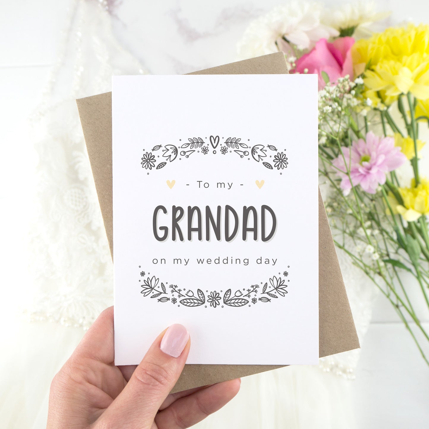 To my grandad on my wedding day. A white card with grey hand drawn lettering, and a grey floral border. The image features a wedding dress and bouquet of flowers.