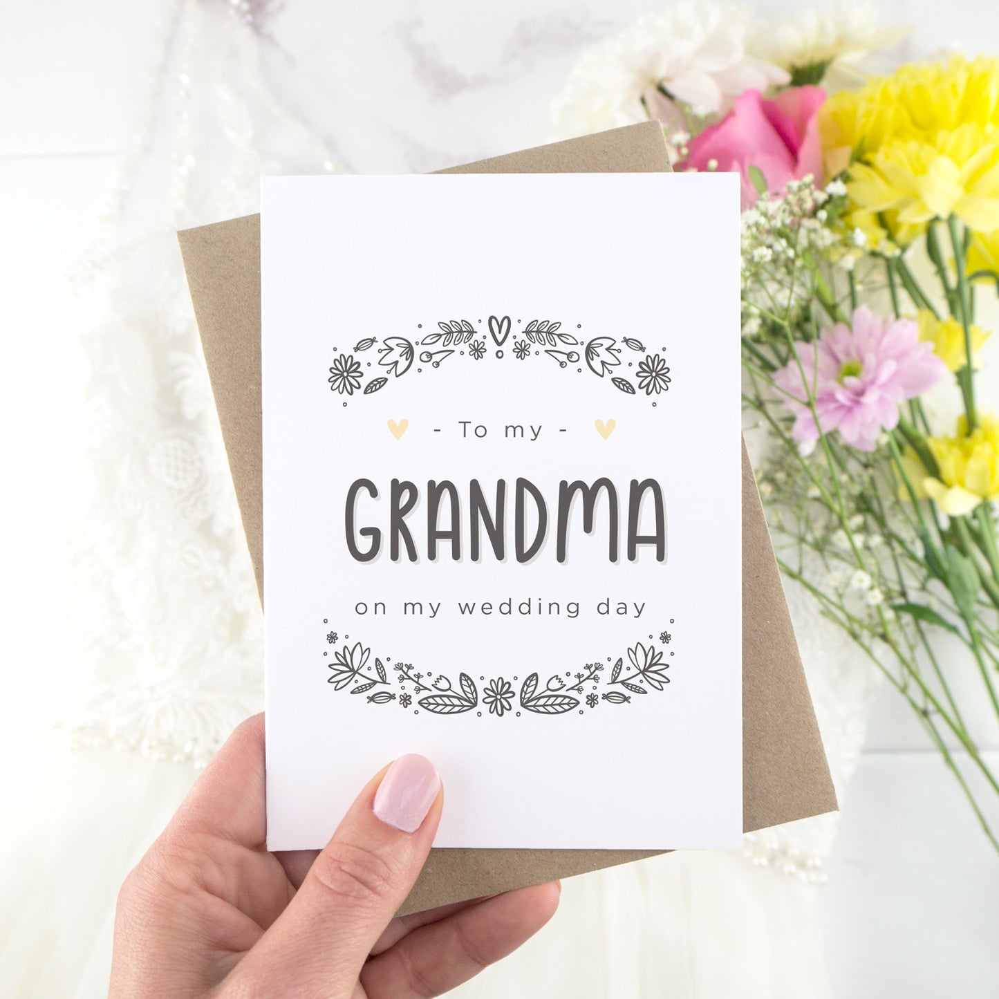 To my grandma on my wedding day. A white card with grey hand drawn lettering, and a grey floral border. The image features a wedding dress and bouquet of flowers.