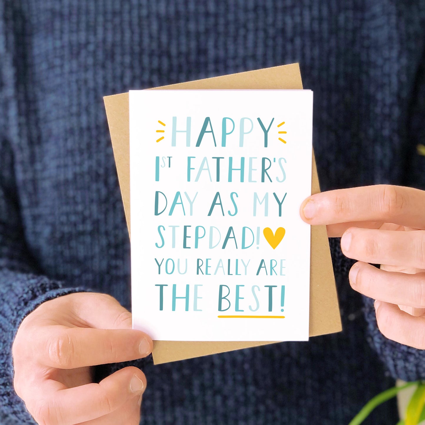 "Happy 1st Father's Day as my Stepdad! You really are the best" First father's day card photographed being held by a man in front of a navy blue jumper.