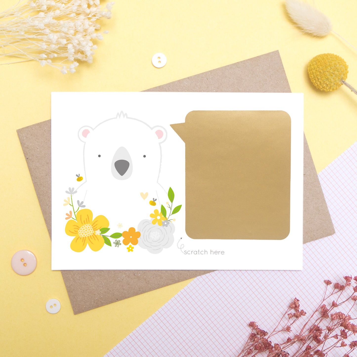 A personalised godparent scratch card before it has been scratched off. This is how the cards will arrive. This one has been shot on a yellow background with floral props. It features a white bear with a yellow theme.