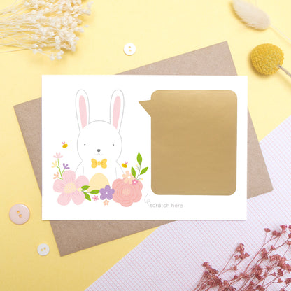 A personalised godparent scratch card before it has been scratched off. This is how the cards will arrive. This one has been shot on a yellow background with floral props. It features a white rabbit with a pink theme.