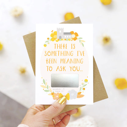 A will you be my godfather scratch and reveal card being held over a white background with pops of yellow. The design features a church, simple florals and a scratch off panel in silver. This is the yellow palette.